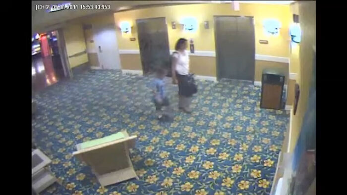 Security camera footage in a hotel hallway showing a woman and child walking near elevators, illustrating intriguing video context. - 13