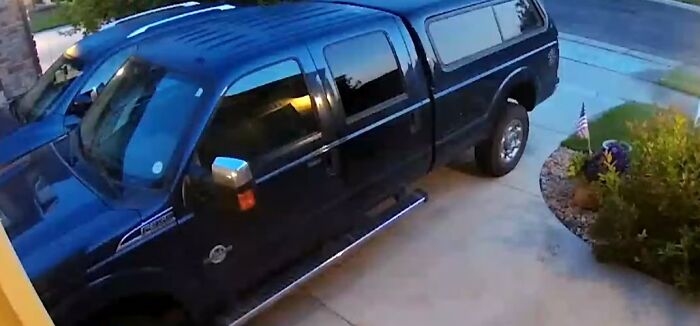 Black pickup truck parked in a residential driveway captured by a security camera for context in videos. - 29