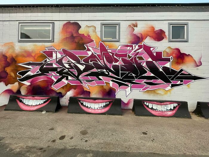Graffiti mural blending realism and abstraction with vibrant colors and large painted smiling mouths on a building wall.