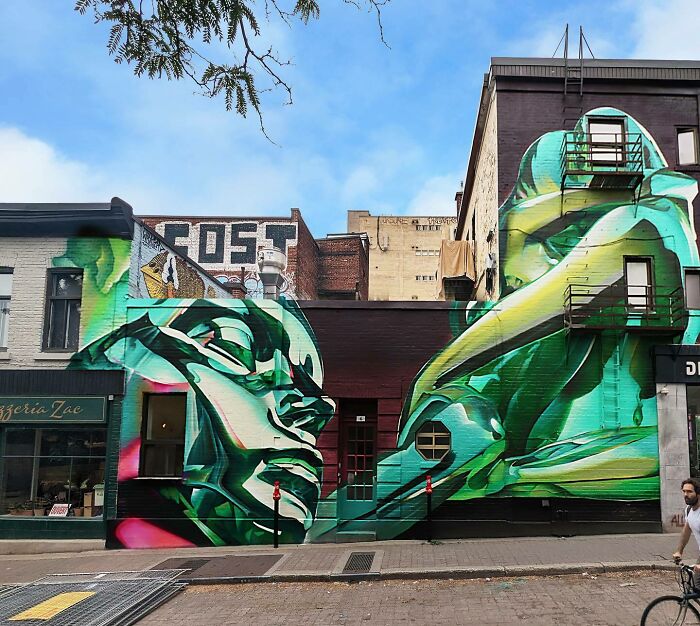 Large vibrant mural blending graffiti, realism, and abstraction painted on urban building walls in a city street setting.