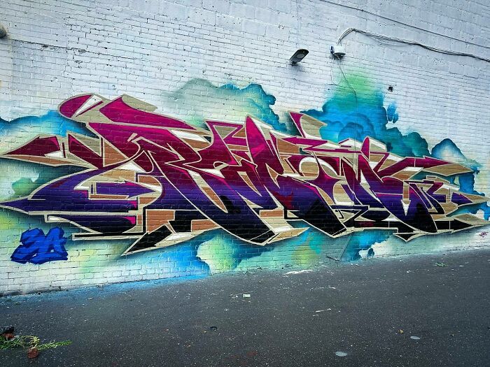 Colorful graffiti mural blending realism and abstraction painted on a white brick wall in urban street setting.