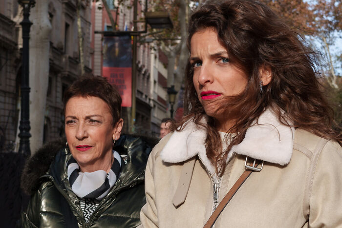 Two women in warm coats walking the street, showcasing diverse cultural expressions captured by photographer traveling countries.