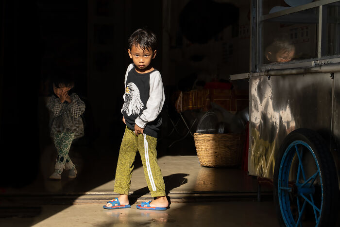 Young boy standing in sunlight near a cart, highlighting cultural beauty captured by a photographer traveling over 50 countries.