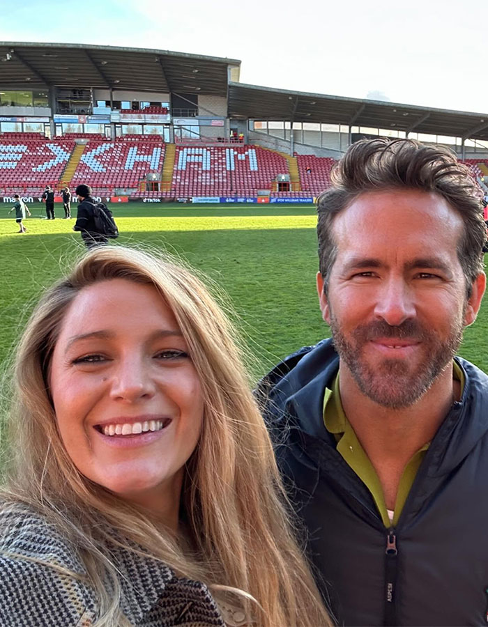 Blake Lively and Ryan Reynolds smiling in a stadium, highlighting Blake Lively leading role in new rom-com.
