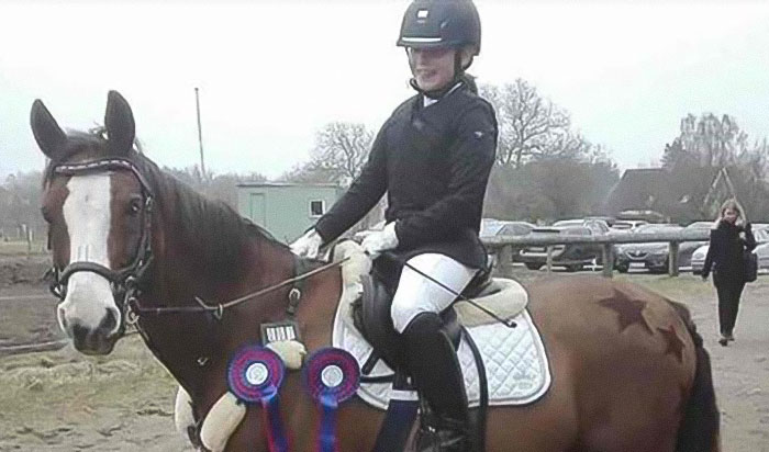 Woman in riding gear on a pony with ribbons, illustrating the donation of her daughter&rsquo;s pony to a zoo for lions.