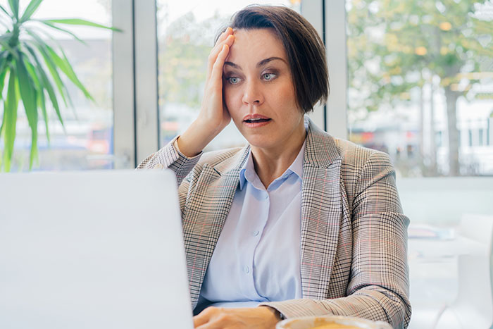 Woman looks surprised at laptop screen, reacting to unexpected email and video file during job interview process.
