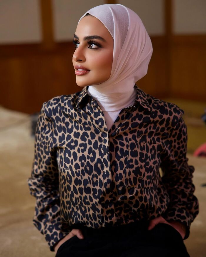 Young woman wearing a patterned blouse and white hijab, showing confidence and style linked to celebrity entitlement.