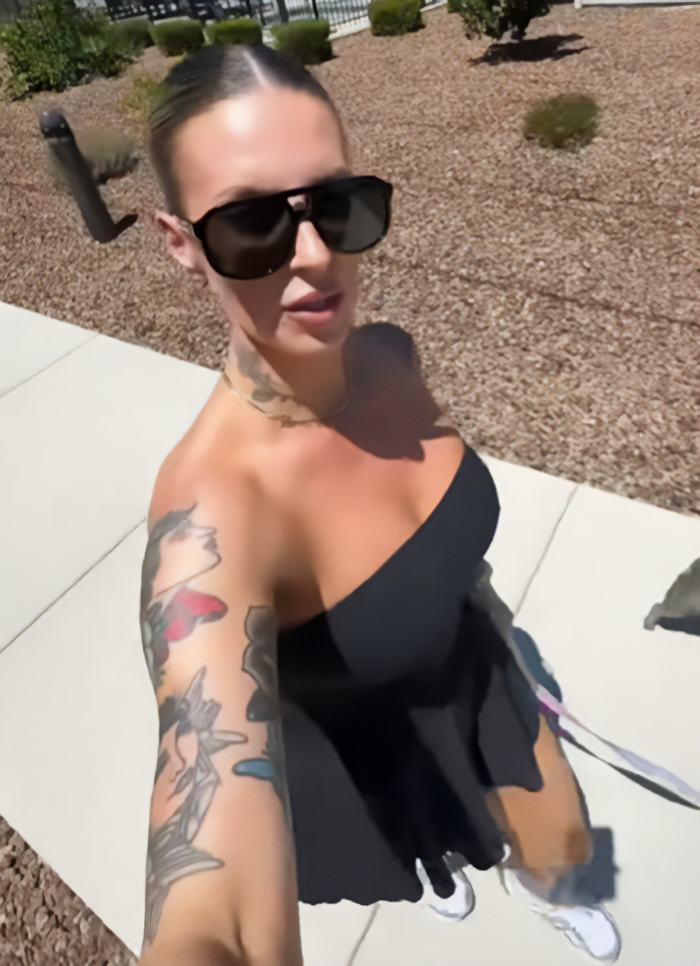 Woman with over 30 tattoos wearing sunglasses and a black dress outdoors, sparking debate over her permanent tattoo regret.