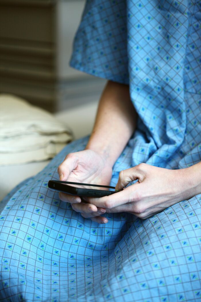 Person in blue patterned dress holding phone, illustrating performative behaviors reflecting society issues.