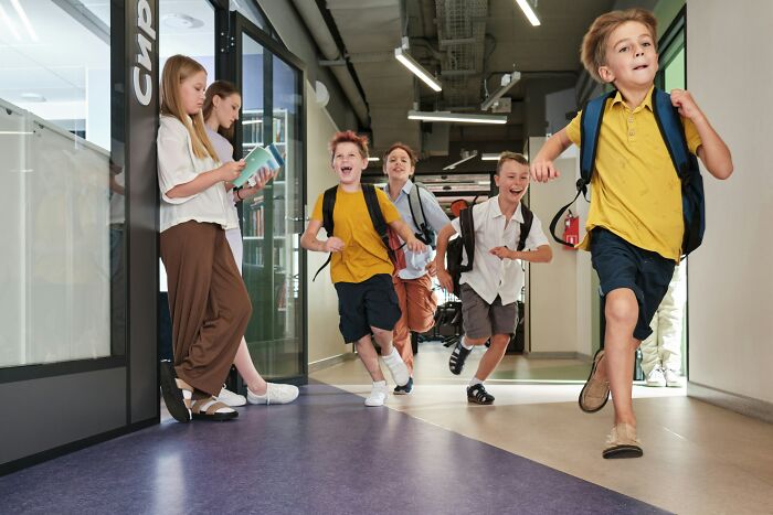 School kids running confidently down a hallway, showcasing wild and confident school kid moments indoors.
