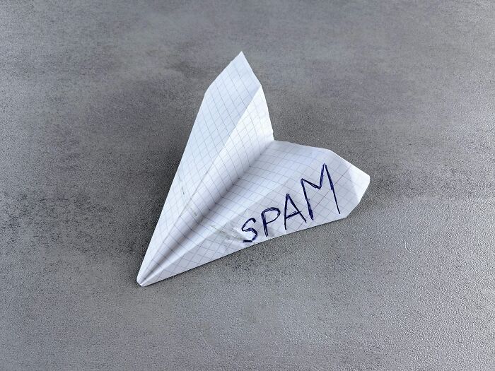 Paper airplane made from graph paper with the word spam written, representing savage roasts and comebacks.