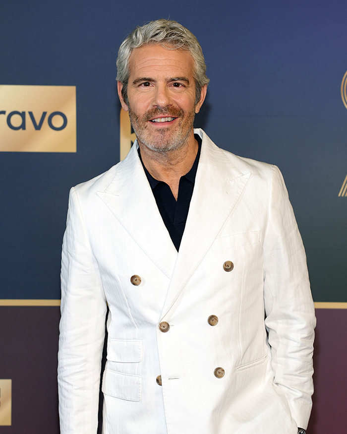 Andy Cohen wearing a white suit at a Bravo event, known for viral roast of anti-LGBTQ activist Kim Davis.