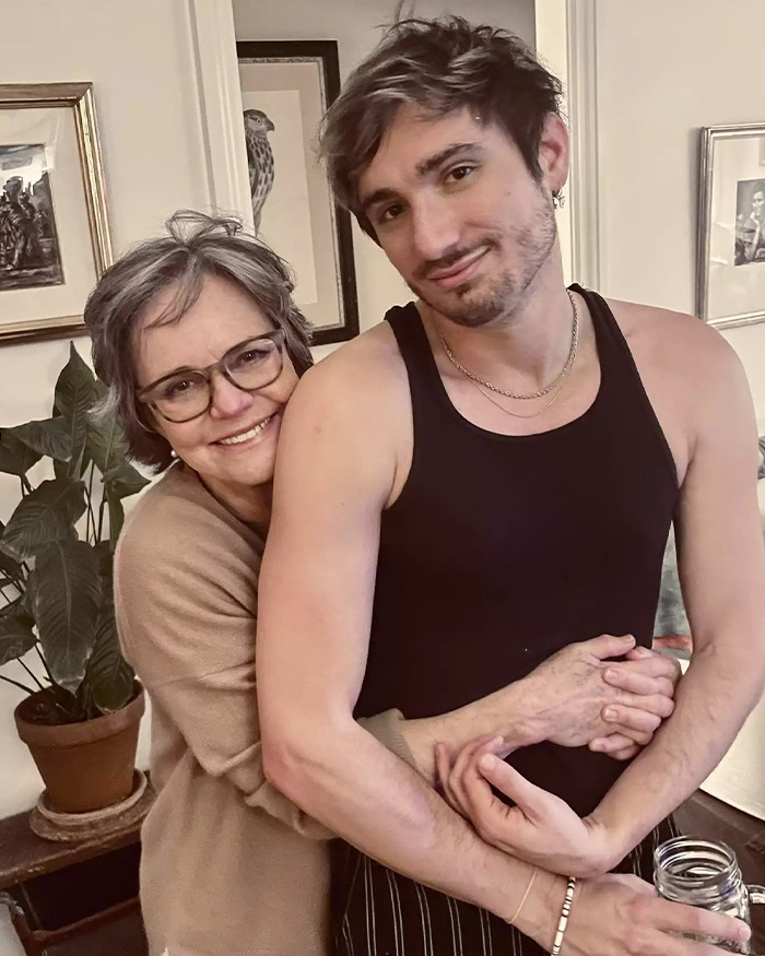 Middle-aged woman smiling and hugging young man in tank top, highlighting Andy Cohen viral roast of anti-LGBTQ activist.