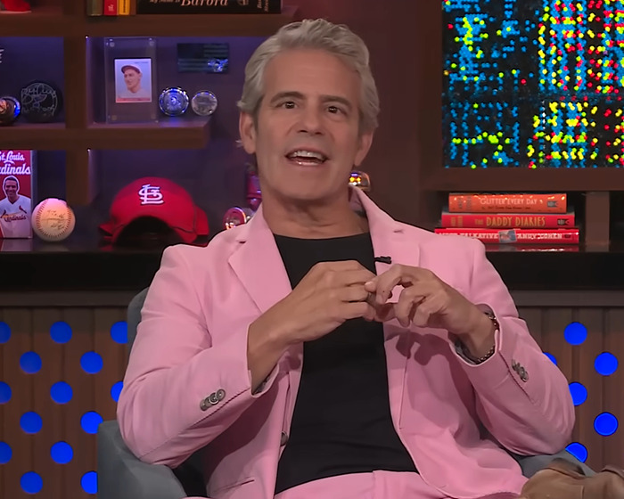 Andy Cohen in a pink suit during a viral moment roasting anti-LGBTQ activist Kim Davis on a TV talk show set.