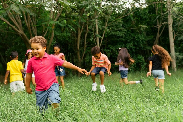 Children playing and laughing outdoors in a green field, representing positive and uplifting good news moments.