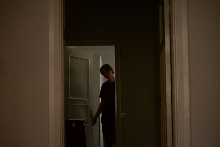 Person cautiously opening a door in a dark hallway, evoking chilling and scary sounds heard by people at night.