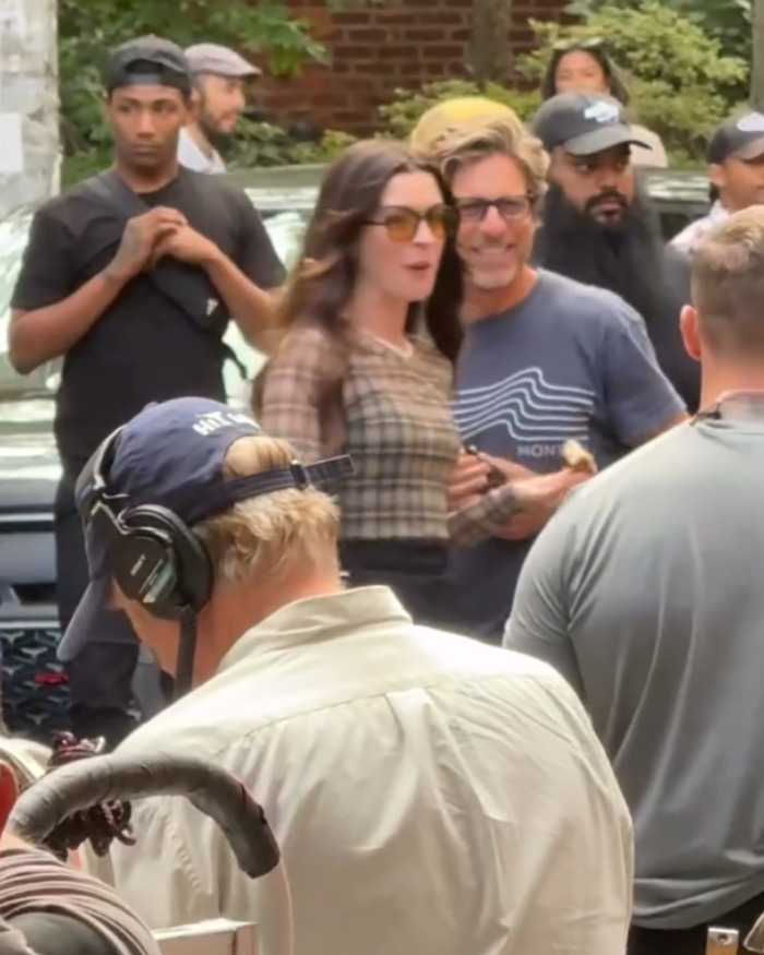 Anne Hathaway surrounded by crew on set, wearing sunglasses, during filming related to heel breaking incident in viral video.