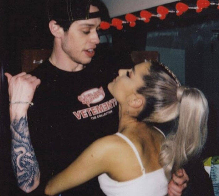 Pete Davidson and a woman closely interacting indoors, highlighting scrutiny on the size of his manhood in the media.