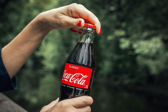 Hand holding a classic Coca-Cola bottle, illustrating ingenious inventions that found new purposes over the years.