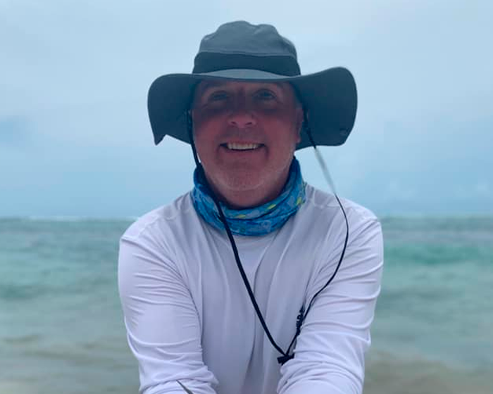 Hombre sonriente con sombrero y pañuelo cerca del agua, relacionado con safari y cornada fatal de búfalo a cazador millonario. Hombre sonriente con sombrero y pañuelo cerca del agua, relacionado con safari y cornada fatal de búfalo a cazador millonario.