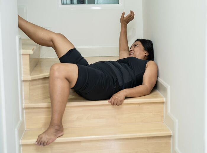 Woman falling on stairs, illustrating dangers to avoid to prevent accidents leading to autopsy tech involvement. - 6