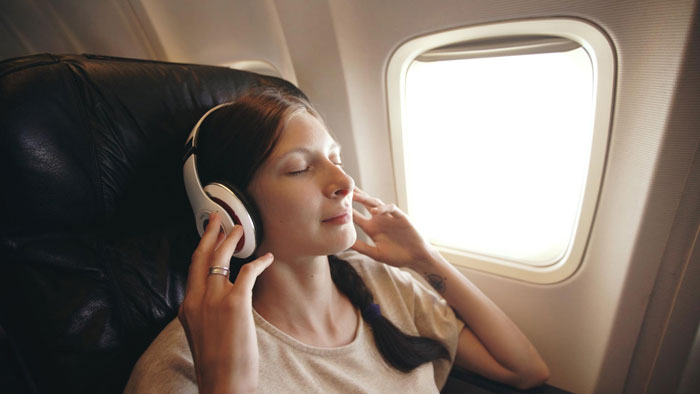 Woman pretending to be asleep in airplane aisle seat, refusing to budge during flight near window light. Woman pretending to be asleep in airplane aisle seat, refusing to budge during flight near window light.