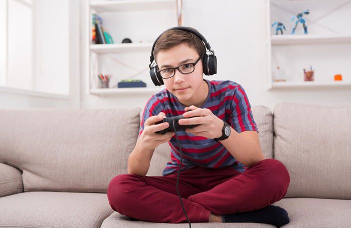 Teen boy playing video games at home, representing nephew before getting a job in family conflict story.