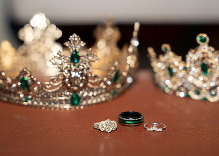 Wedding rings and ornate crowns with green gems on a surface, highlighting bride and wedding photographer themes.