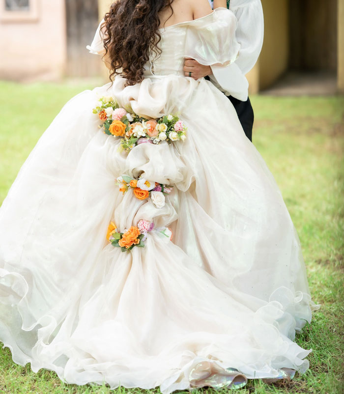Bride in a flowing wedding dress adorned with flowers outdoors, illustrating wedding photographer and dog with GoPro concept.