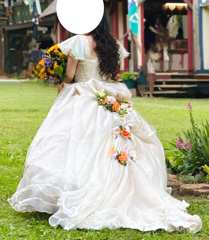 Bride in a flowing white wedding dress holding a colorful bouquet outdoors, highlighting wedding photographer costs debate.