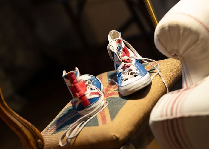 Pair of worn sneakers with a Union Jack design placed on a vintage patterned chair, symbolizing unique wedding photography choices.