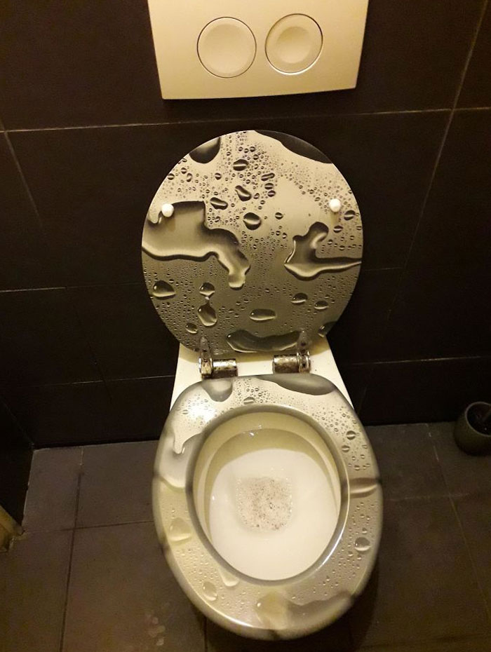 Toilet seat with water droplet design creating a confusing and ineffective design fail in a bathroom setting.