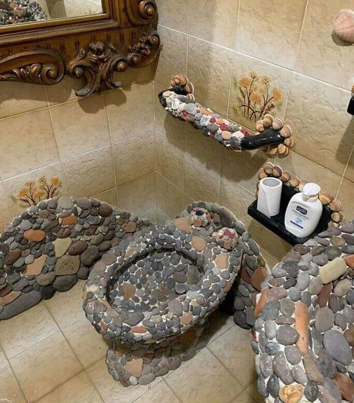 Bathroom with a toilet and sink covered entirely in decorative stones, showcasing unusual design fails.