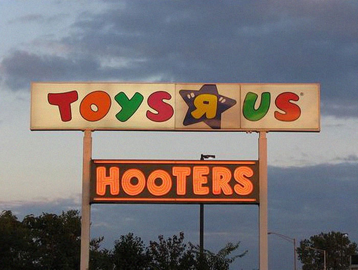 Misleading design fail showing a Toys R Us sign above a Hooters sign causing confusing brand association outdoors.