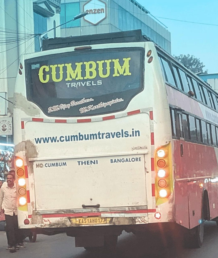 Bus with poorly designed company name CUMBUM Travels causing a design fail on a busy street.