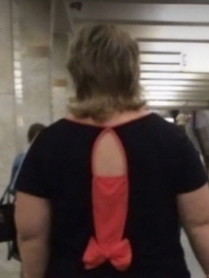 Person wearing a black shirt with an unusual red fabric design on the back showing a design fail in clothing.