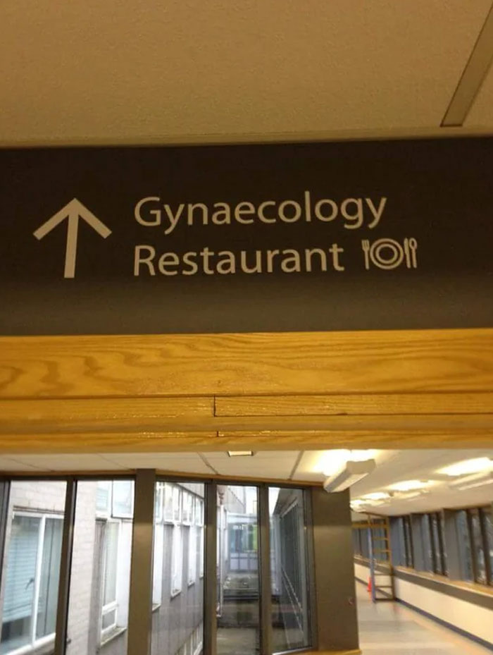 Sign directing to both gynaecology and restaurant, showcasing a confusing design fail in public building signage.