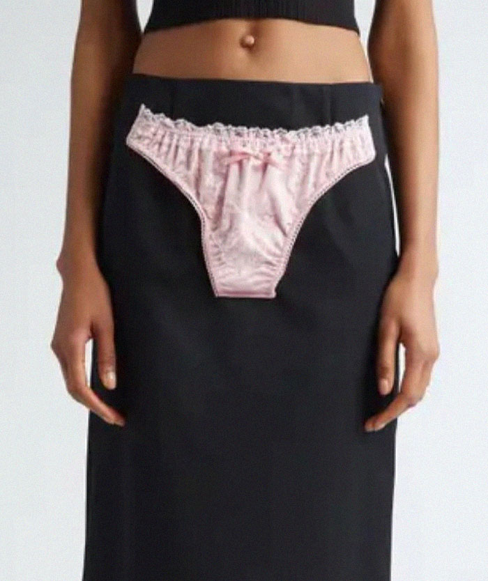 A person wearing a black skirt with a small pink underwear sewn onto the front as a design fail example.