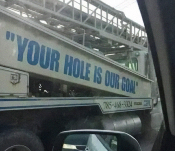 Construction truck with poorly designed slogan Your hole is our goal, showcasing a notable design fail on the vehicle side panel.