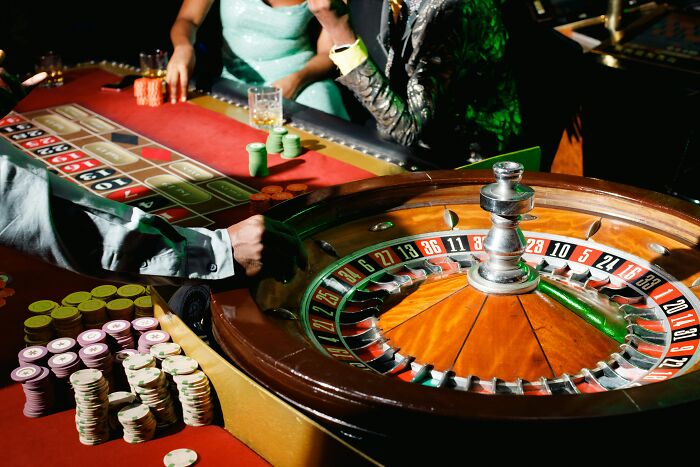 Casino roulette table with stacks of chips and players placing bets, illustrating the wealth gap perspective.