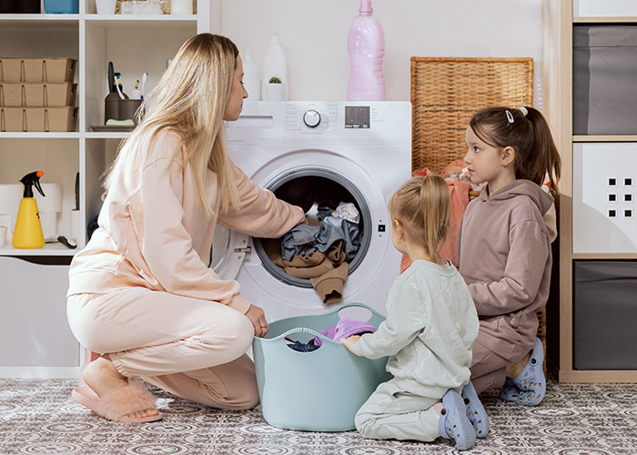 Mom and kids using unhinged mom hacks for laundry, blending genius and chaos in a home setting.