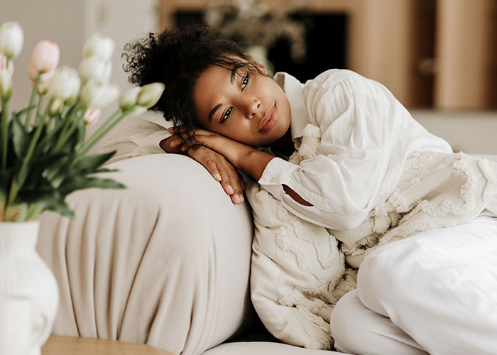 Woman resting thoughtfully on a couch, illustrating unhinged mom hacks blending genius and chaos in everyday life.