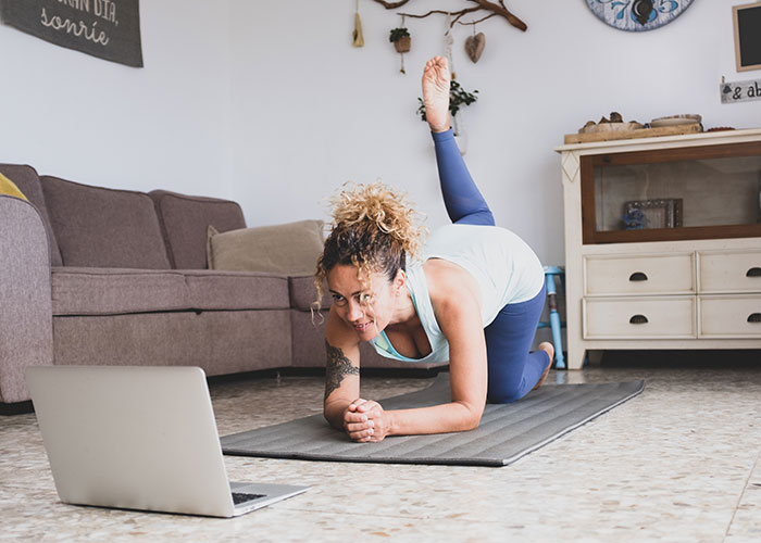 Woman practicing yoga on a mat at home, following unhinged mom hacks that toe the line between genius and chaos.