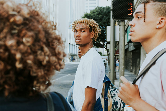 Three young people standing on a city street corner, illustrating street smart tips and tricks in an urban setting.
