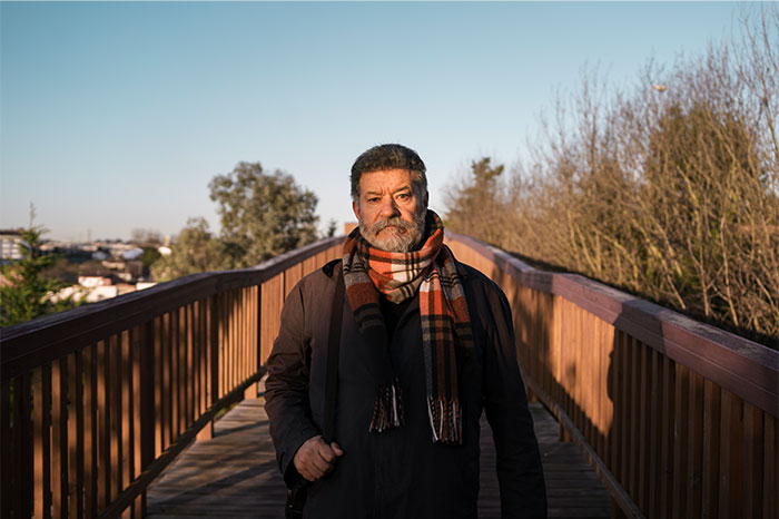 Man wearing a scarf standing on a wooden bridge during daylight, illustrating street smart tips and tricks concept.
