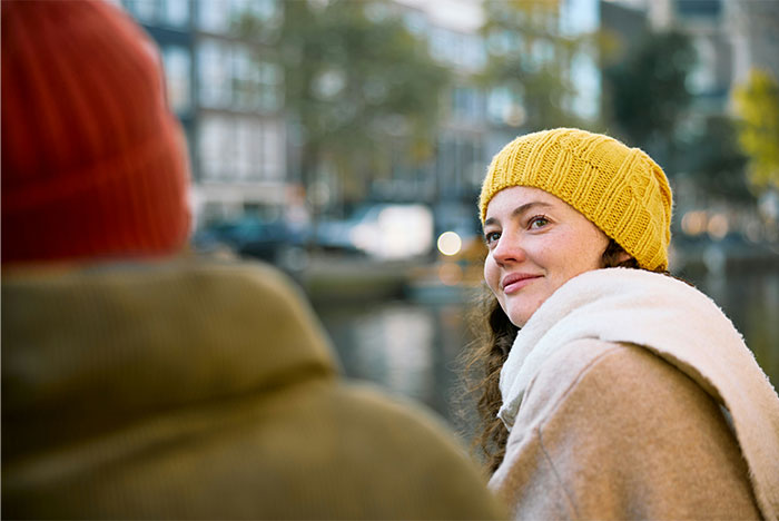 Two people dressed warmly, one woman in a yellow hat smiling, representing street smart tips and tricks outdoors.