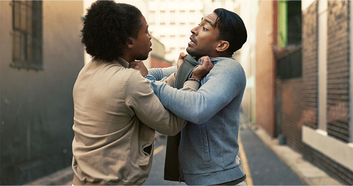 Two men in an urban alley demonstrating street smart tips for conflict resolution and personal safety.