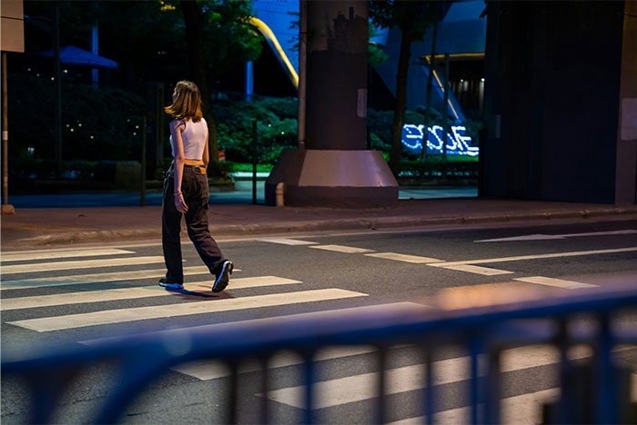 Person crossing street at night in urban setting, illustrating concepts related to street smart tips and tricks.