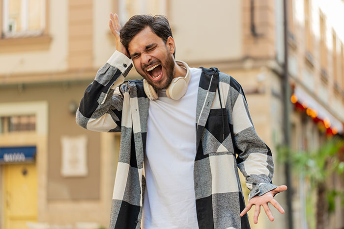 Man expressing frustration outdoors, illustrating common reverse culture shocks experienced by Americans moving back home.