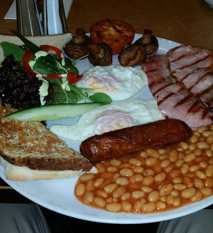 Plate of traditional breakfast with eggs, sausage, beans, and grilled vegetables illustrating reverse culture shocks for returning Americans.